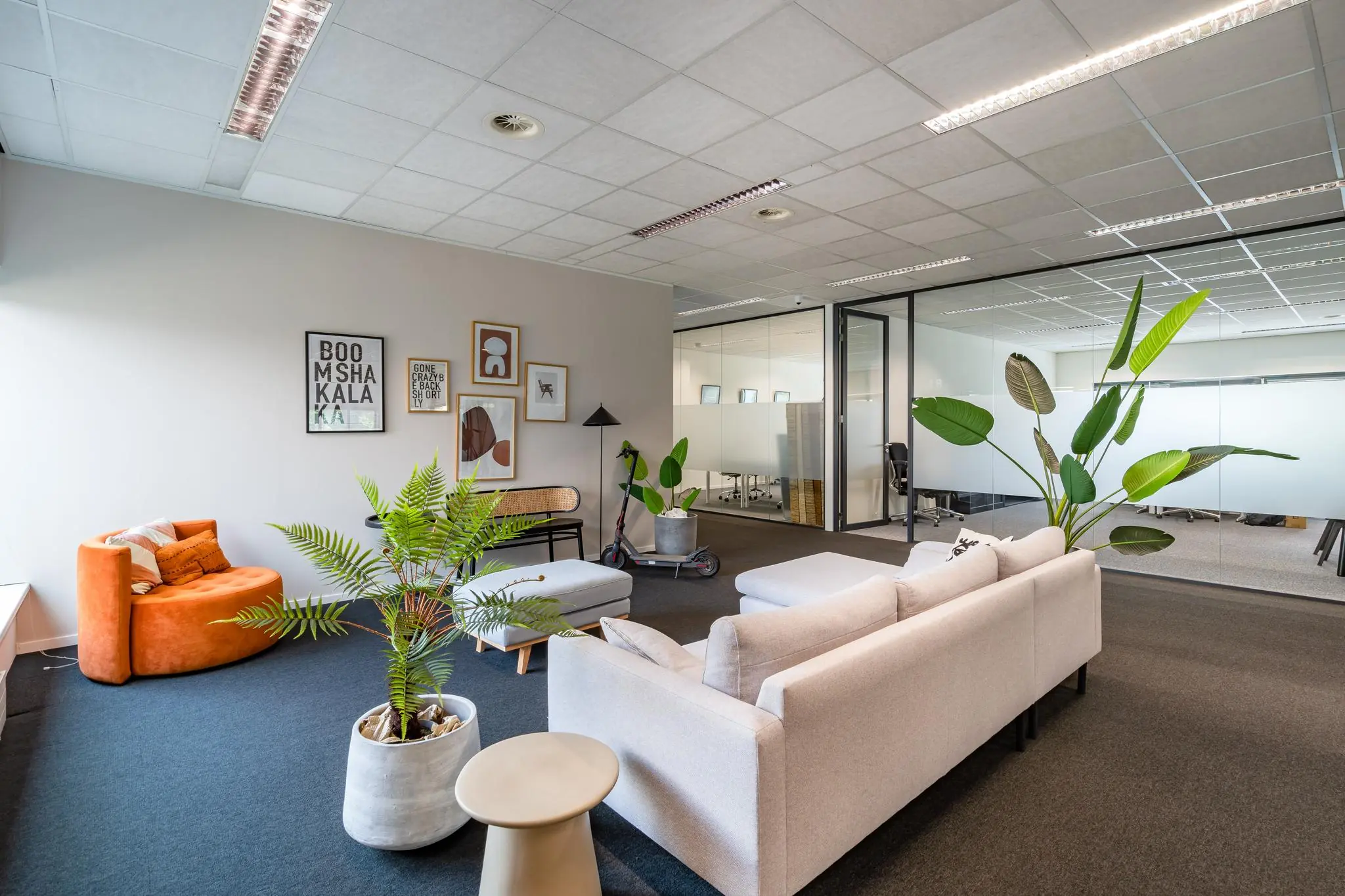 Moderne loungehoek in een kantoorpand aan het Rivium Boulevard, met comfortabele zitmeubels, kamerplanten en glazen vergaderruimtes op de achtergrond.